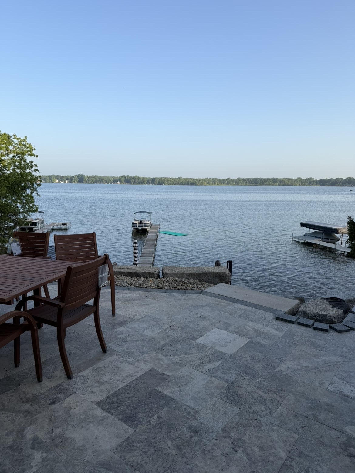 Custom paver patio installation adjacent to lakeside wall