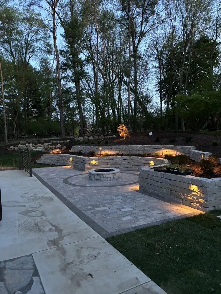 Evening perspective of lit outdoor fire pit on paver patio