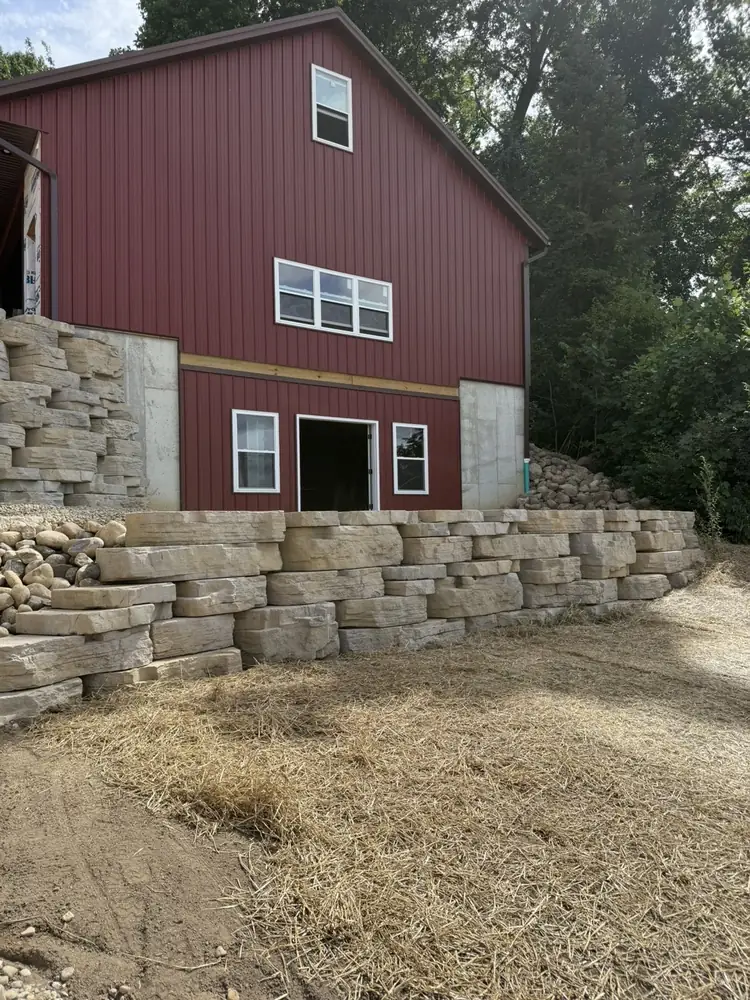 Integrated stone steps connecting upper hillside tier to paver patio